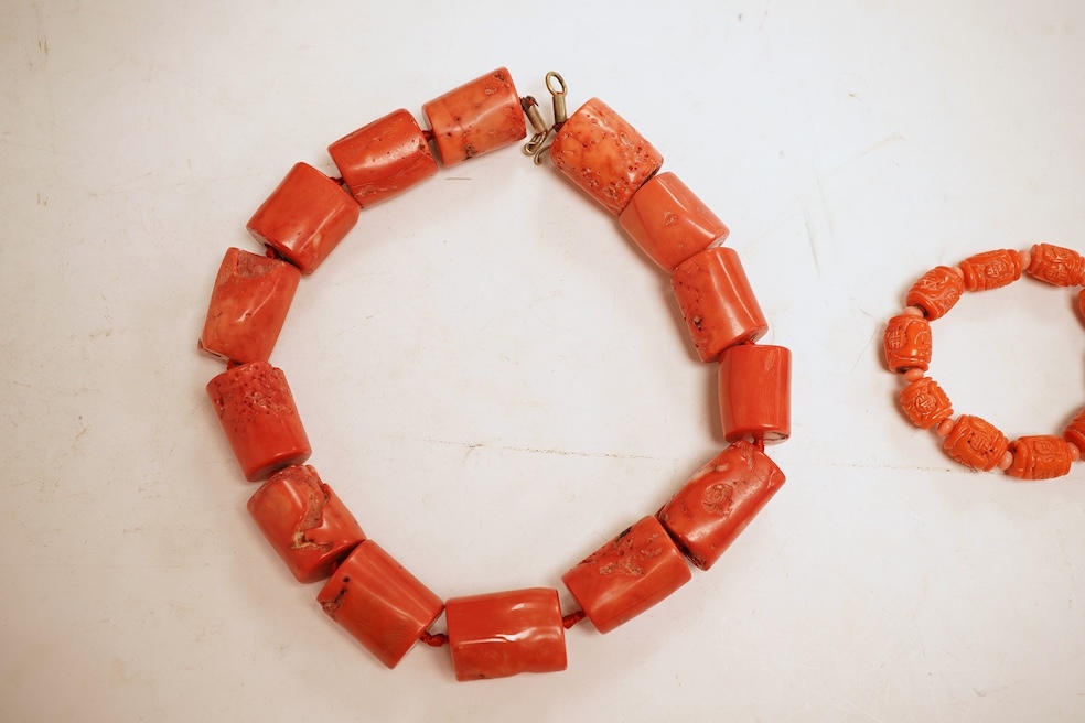 Two coral bead necklaces, one composed of large cylindrical coral beads, approximately 2.5-3.5cm each, total length 49cm; and a bracelet composed of carved coral beads spaced by smaller pink coral beads, on an elasticate